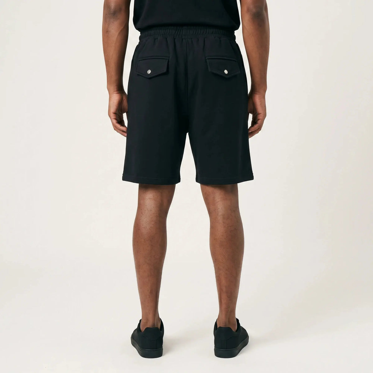 Black FJ033 Iconic Badge shorts, viewed from the back, featuring an elastic waistband and two snap-button pockets.