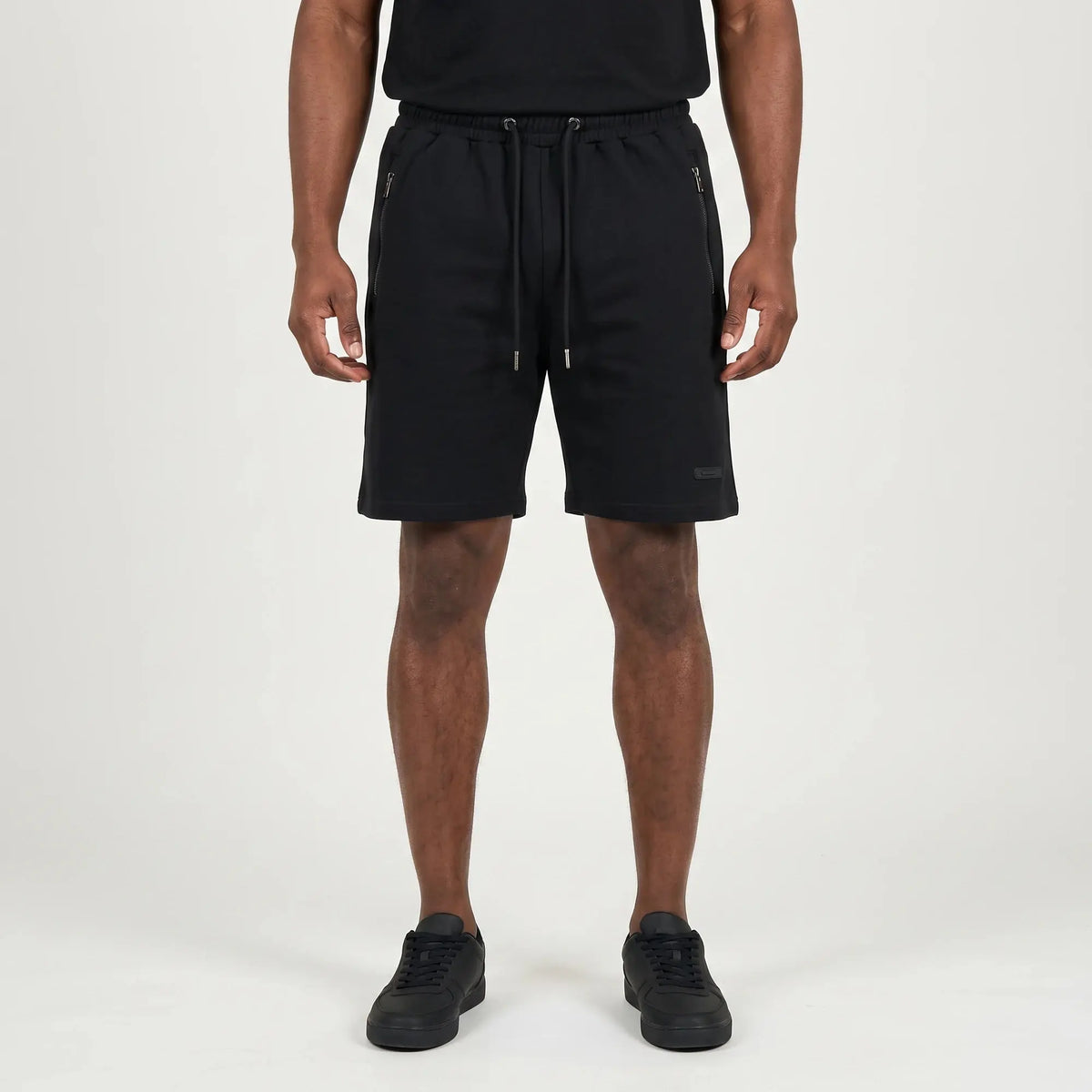 Black FJ033 Iconic Badge Shorts for men, featuring an adjustable drawstring waist, side zipper pockets, and a subtle iconic