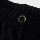 Close-up of the black FJ033 Iconic Badge Shorts waistband, featuring an elasticated design, black drawstring, and a metallic