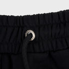 Close-up of black FJ033 Iconic Badge Shorts, featuring an elastic waistband with a black drawstring and a silver branded