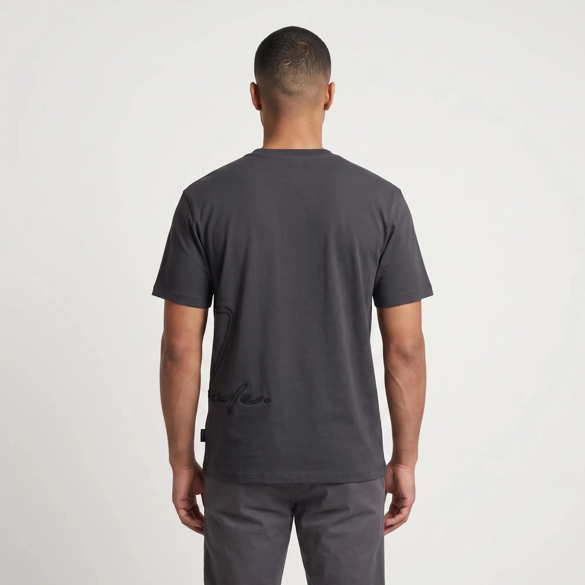 Back view of the FT070 Signature Side Print Relaxed Fit T-Shirt in dark grey, showing a subtle black graphic on the lower